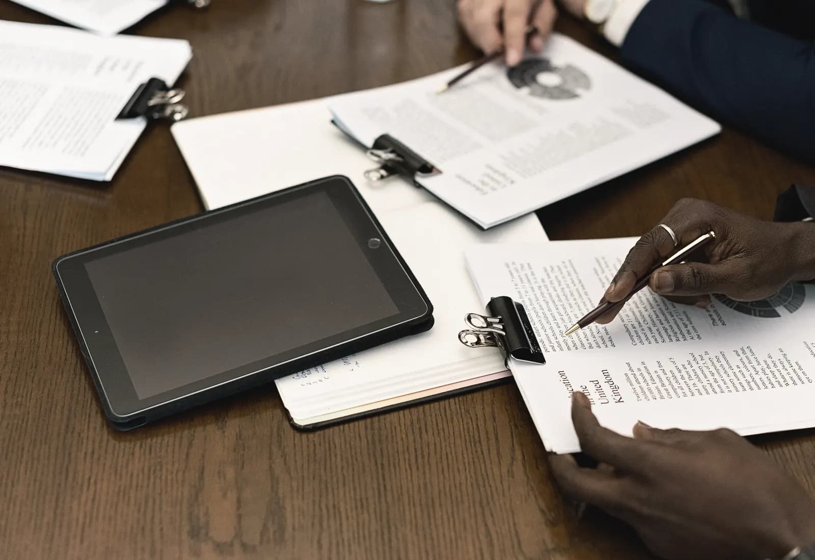 A small team reviewing printed reports together at a wooden table